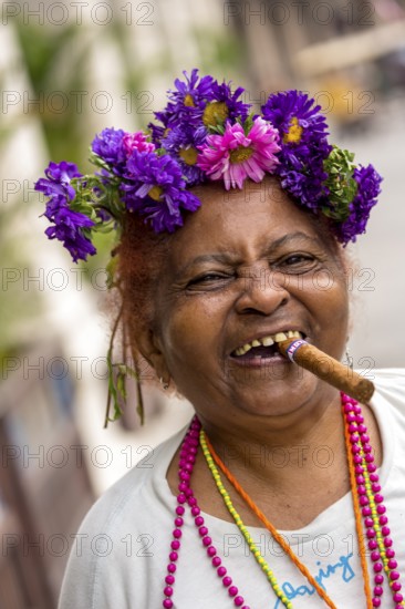 Old Cuban woman with flowers and cigar posing for a tip for tourists, La Habana, Havana, Cuba,