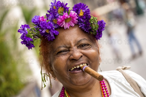 Old Cuban woman with flowers and cigar posing for a tip for tourists, La Habana, Havana, Cuba,