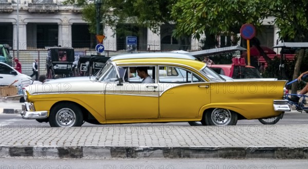 Yellow vintage car in street scene, Old American street cruiser on the streets of Havana, Taxi, La