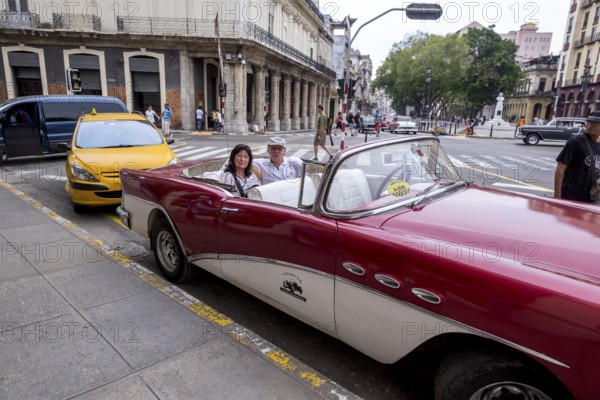 Tourists in a red convertible, red vintage convertible in the street scene, old American street
