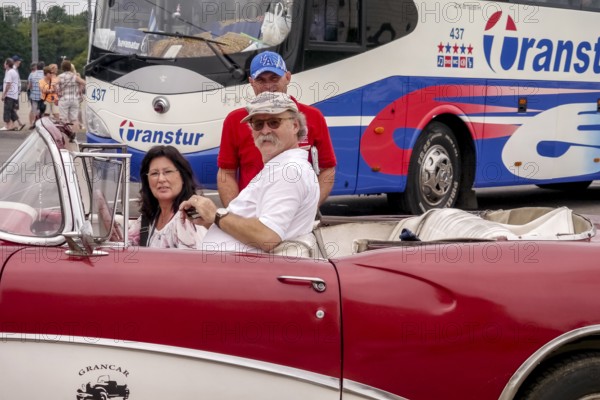 Tourists in a red convertible, red vintage convertible in the street scene, old American road