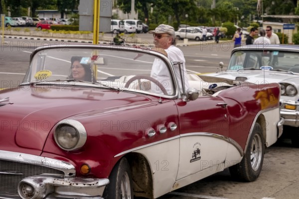 Tourists in a red convertible, red vintage convertible in the street scene, old American road