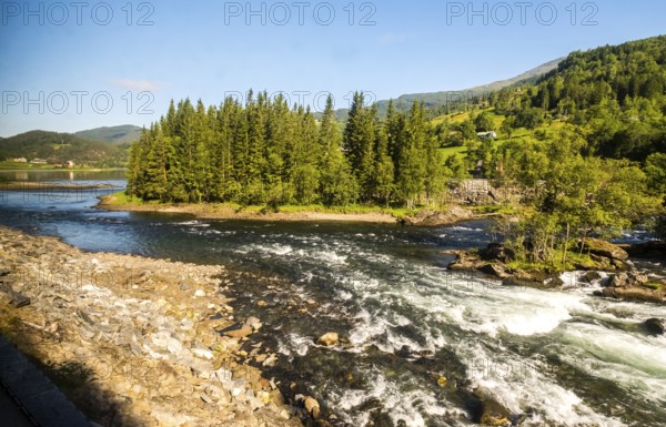 Fjord near the city of Bergen, small island, spruces, rapids, large stones, blue sky, Hordaland,