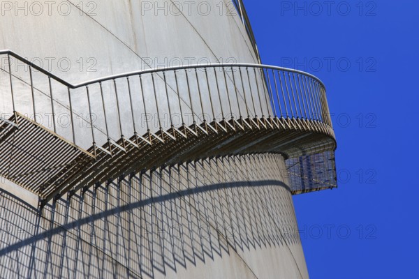 Metal staircase with striking shadow play on the side of a large tank, elevated tank, chemical,