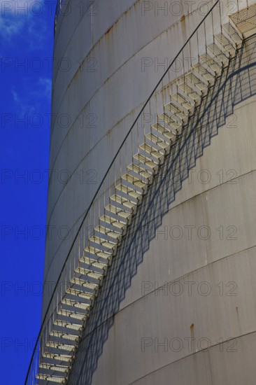 Metal staircase on a large industrial gas tank under a clear blue sky, elevated tank, chemical,