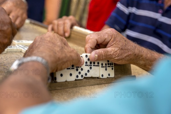 Old Cubans playing dominoes at a table on the street in the city centre of Trinidad, Trinidad,