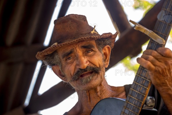 Sugar cane farmer in Valle de los Ingenios plays guitar for the tourists, Trinidad, Cuba, Sancti