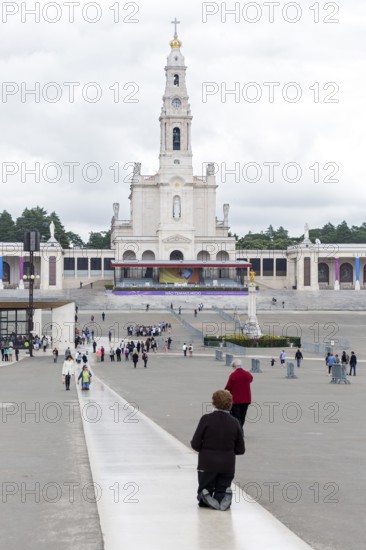 Penitents slide on their knees across the forecourt of the Basilica of Fatima, Fátima, District of