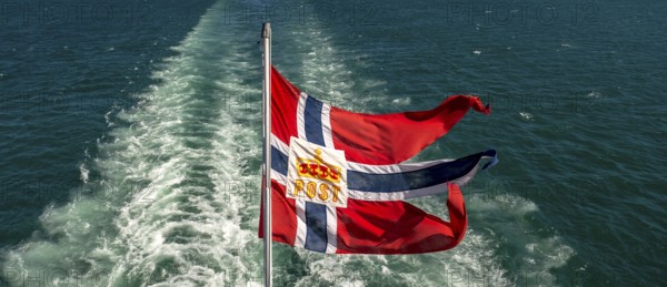 The post symbol on Norwegian flag of a Hurtigruten ship, foaming spray, Trondheimfjord, Agdenes,