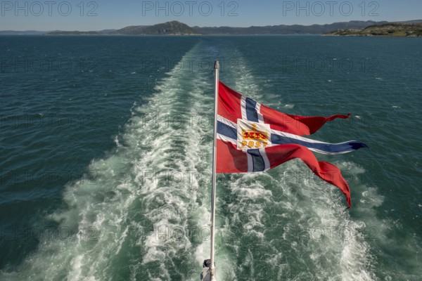 The post symbol on Norwegian flag of a Hurtigruten ship, foaming spray, Trondheimfjord, Agdenes,