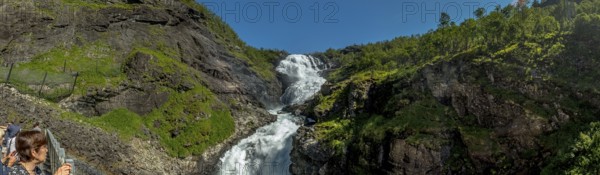 Kjosfossen waterfall, tourist looking at waterfall near Fureberget, rock faces, trees, sky, Flåm,