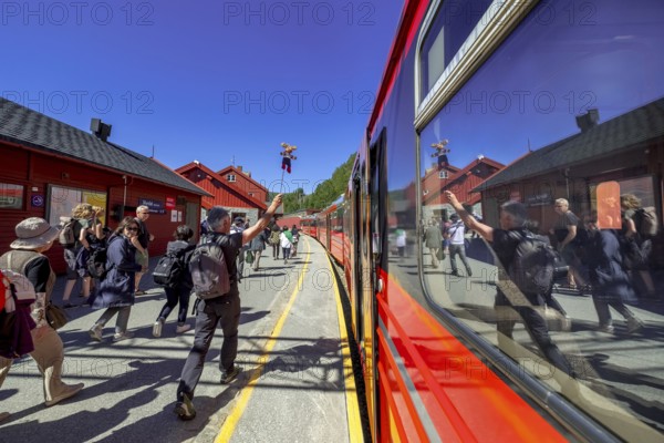 Tour guide reflected in the train window, tourists on the platform, Bergen railway station, Myrdal,
