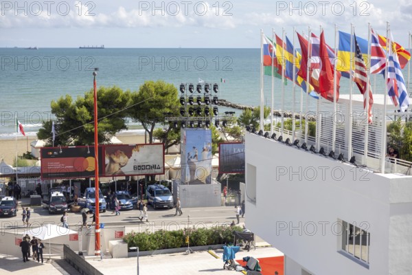 Venice, Italy - 2 September 2025: Spectators and guests walk past a film poster in front of the