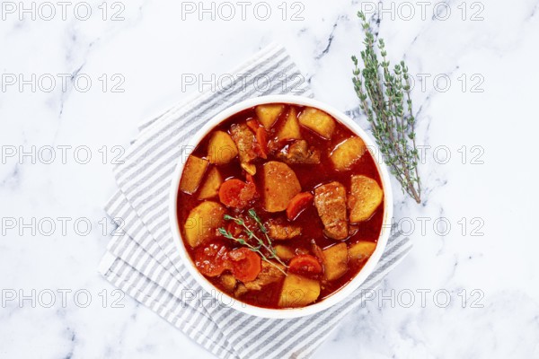 Meat goulash with potatoes and carrots, sweet peppers, in a saucepan, top view, traditional