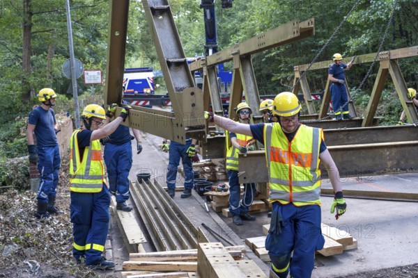 Construction of a temporary bridge over a slipped road crossing a stream, by the bridge