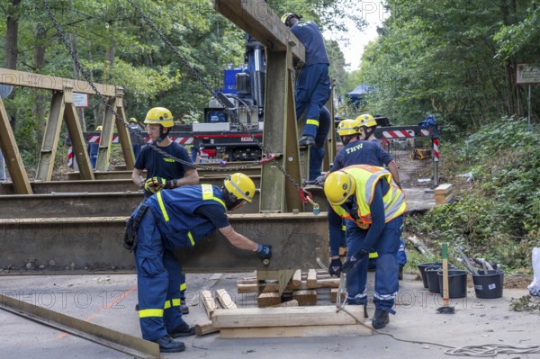 Construction of a temporary bridge over a slipped road crossing a stream, by the bridge