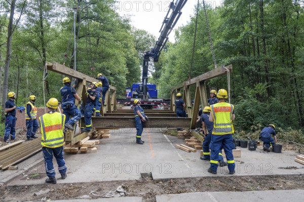 Construction of a temporary bridge over a slipped road crossing a stream, by the bridge