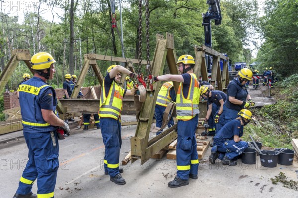 Construction of a temporary bridge over a slipped road crossing a stream, by the bridge