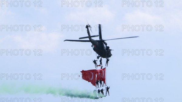 Türkiye special operations police hang from a helicopter with ropes, carrying weapons and unfurling