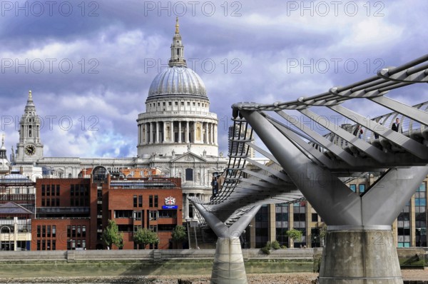 St Paul's Cathedral next to the Millennium Bridge under a dramatic sky, London, England, United