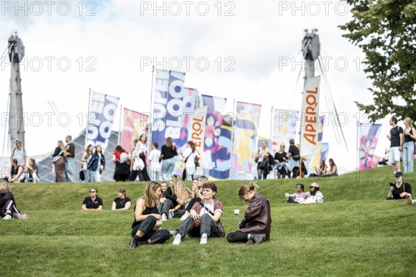 Visitors relaxing in a meadow at the Superbloom Festival, Day 1 in the Olympic Park, Munich,