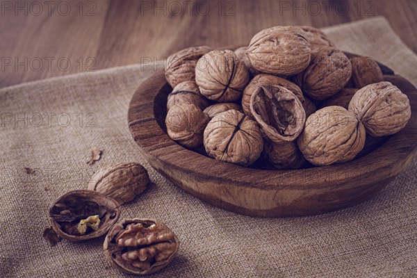Freshly picked walnuts, in a wooden bowl, on a wooden table, rustic style, no people
