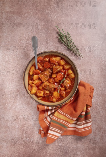 Meat goulash with potatoes and carrots, sweet peppers, in a saucepan, top view, traditional