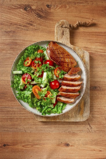 Delicious grilled duck breast served with fresh garden salad and cherry tomatoes at a rustic dining