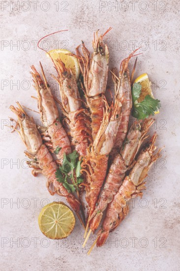 Shrimps on skewers, Grilled, spread on a marble surface, garnished, with lemon slices, and fresh