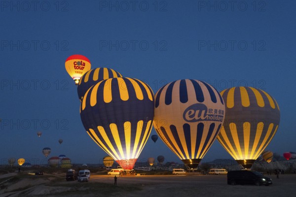 Several illuminated hot-air balloons decorate the sky at dawn, Göreme National Park, Göreme Tarihî