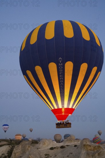 Balloons of different colours rise calmly into the morning atmosphere over the vast terrain, Göreme