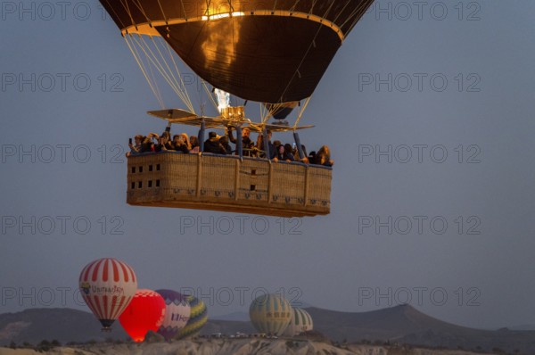 A hot air balloon with passengers in the basket floats under the morning sky, Göreme National Park,