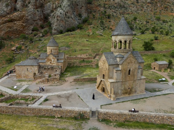Old church in rural area with stone buildings and green landscape surrounded by mountains, aerial