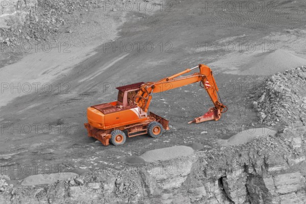 Tracked red excavator in rocky quarry ambiance