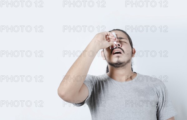 Young man with nosebleed on isolated background. Person with sinusitis or epistaxis. Concept of a