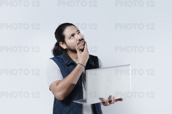 Thoughtful man with hand on chin using computer on isolated background. Man thinking holding a