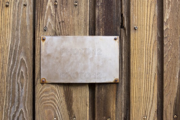 Old metallic sign on wooden board