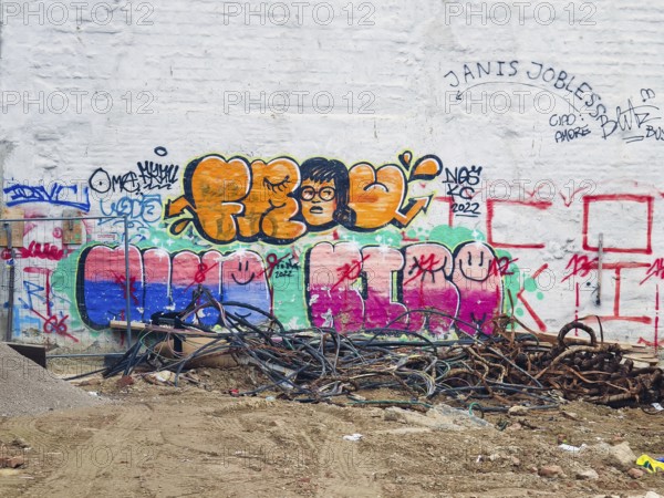 A hodgepodge of colourful graffiti adorns a white wall with cables on the floor Mariahilferstrasse