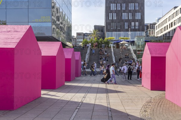 Twelve houses in bright magenta stand on Stuttgart's Schlossplatz in front of the art museum. The