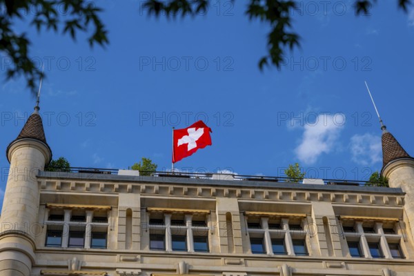 Beautiful Swiss Flag on a Old Building with Towers Against Blue Sky in a Sunny Summer Day in