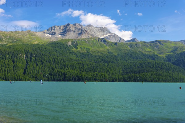 Windsurfing and Wingsurfing on Alpine Lake Silvaplana in a Sunny Summer Day with Mountain in