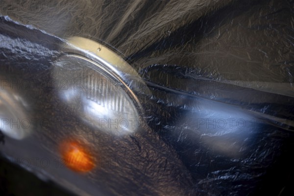 Car Lamps on the Front of a an Old Classic Car Covered with Plastic Protection in Switzerland