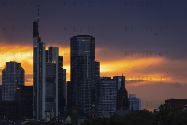 The sun breaks through the clouds behind the Frankfurt banking skyline shortly in front of setting,