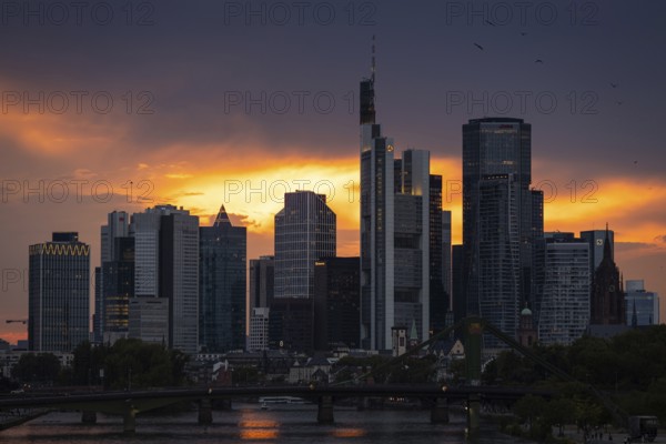 The sun breaks through the clouds behind the Frankfurt banking skyline shortly in front of setting,