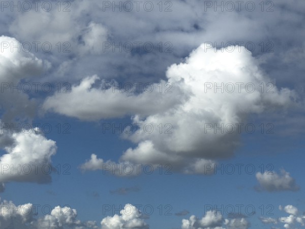 Cumulus clouds at the bottom edge of the image, large white cumulonimbus cluster cloud towering in