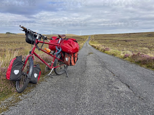A fully loaded bicycle stands on a long country road in a wide landscape, Adventure, Cycling tour,