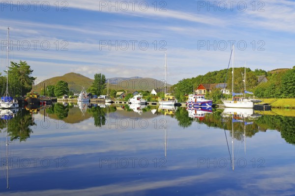 Calm river landscape with anchored boats and clear reflections, Caledonian Canal, Fort William,