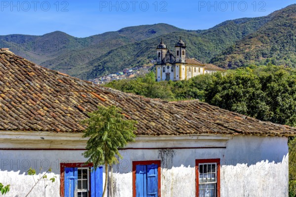 Old weathered colonial house with a baroque church and mountain in the background in the historic