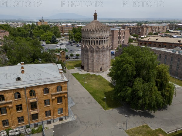 A round tower in an urban setting with surrounding trees and historic buildings, aerial view, Holy