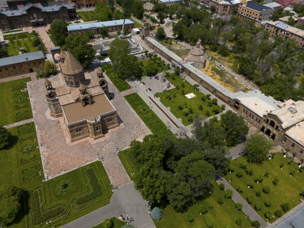 Bird's eye view of historic church surrounded by manicured gardens in an urban setting, aerial